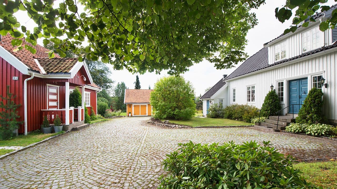 Gårdstun med brostein og hus malt i hvitt, gult og rødt.