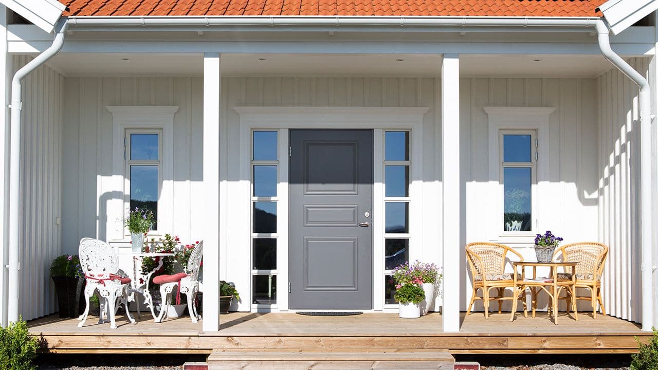 Hvitt hus med stort inngangsparti med klassisk ytterdør og sidefelt.