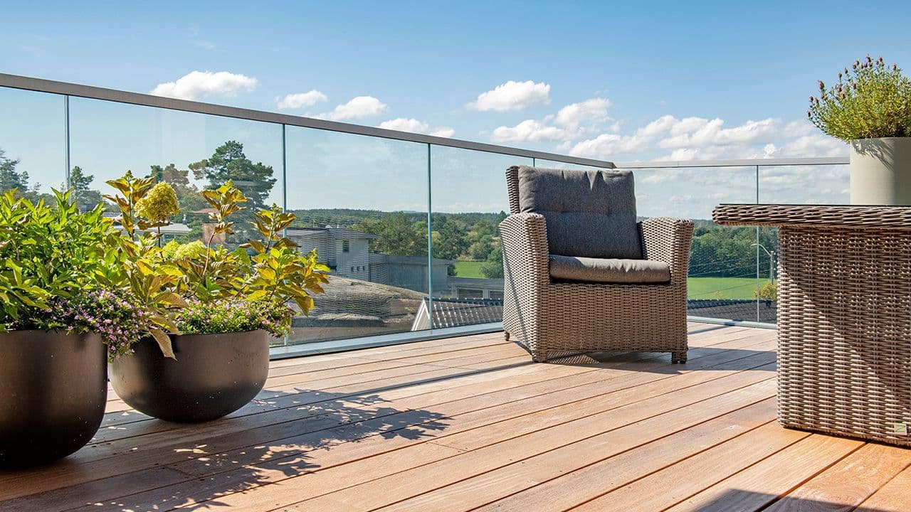 Glassrekkverk på terrasse med utsikt over fjord.
