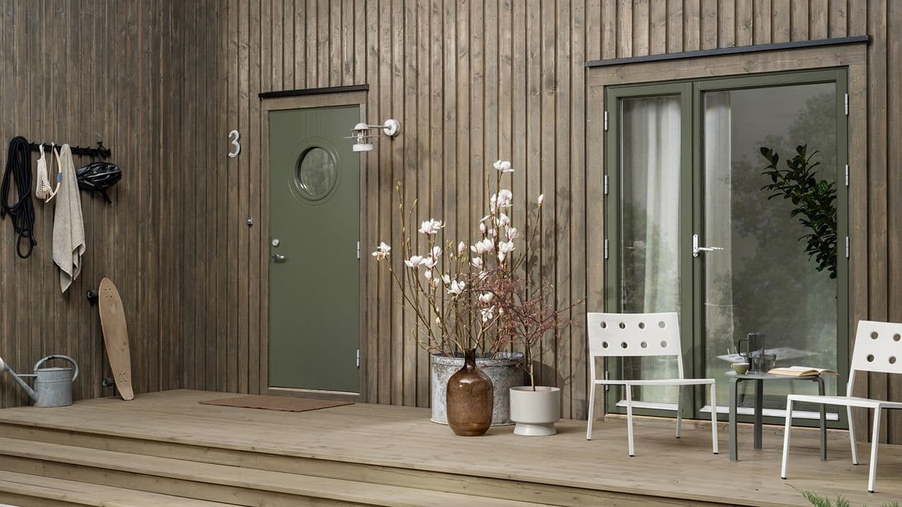 Hus malt med utebeis TREBITT Oljebeis 90031 Eldet Grå, dør: Drygolin Nordic Extreme Vindu og dør 8413 Herregårdsgrønn og TREBITT Terrassebeis 9074 Nordisk Tre.