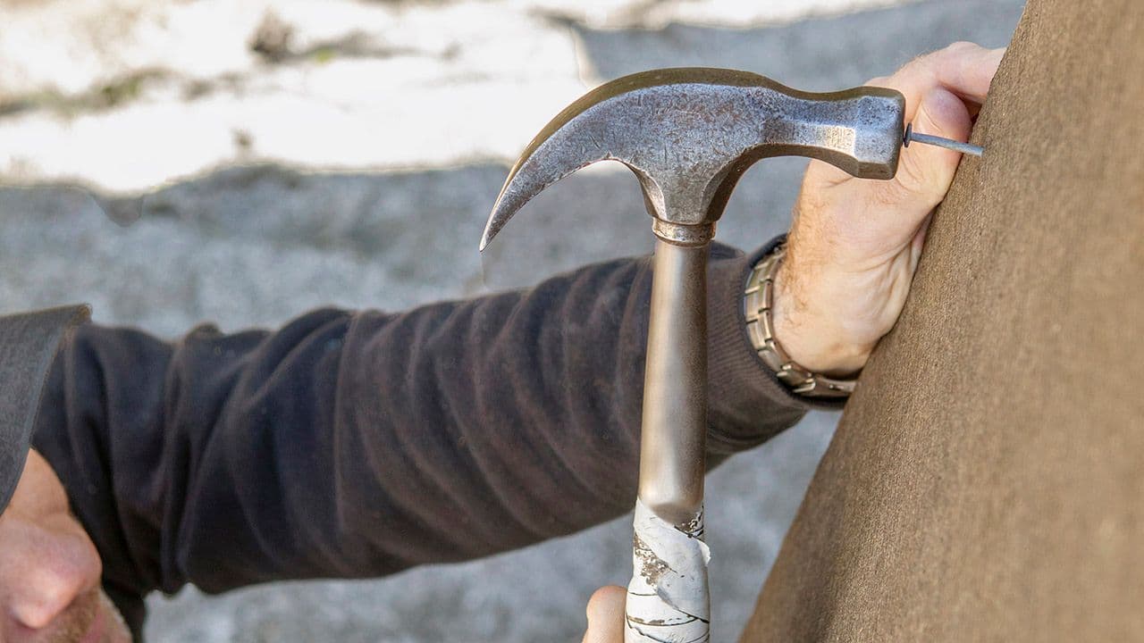 Mann som spikrer på plass trefiberisolasjon på vegg.