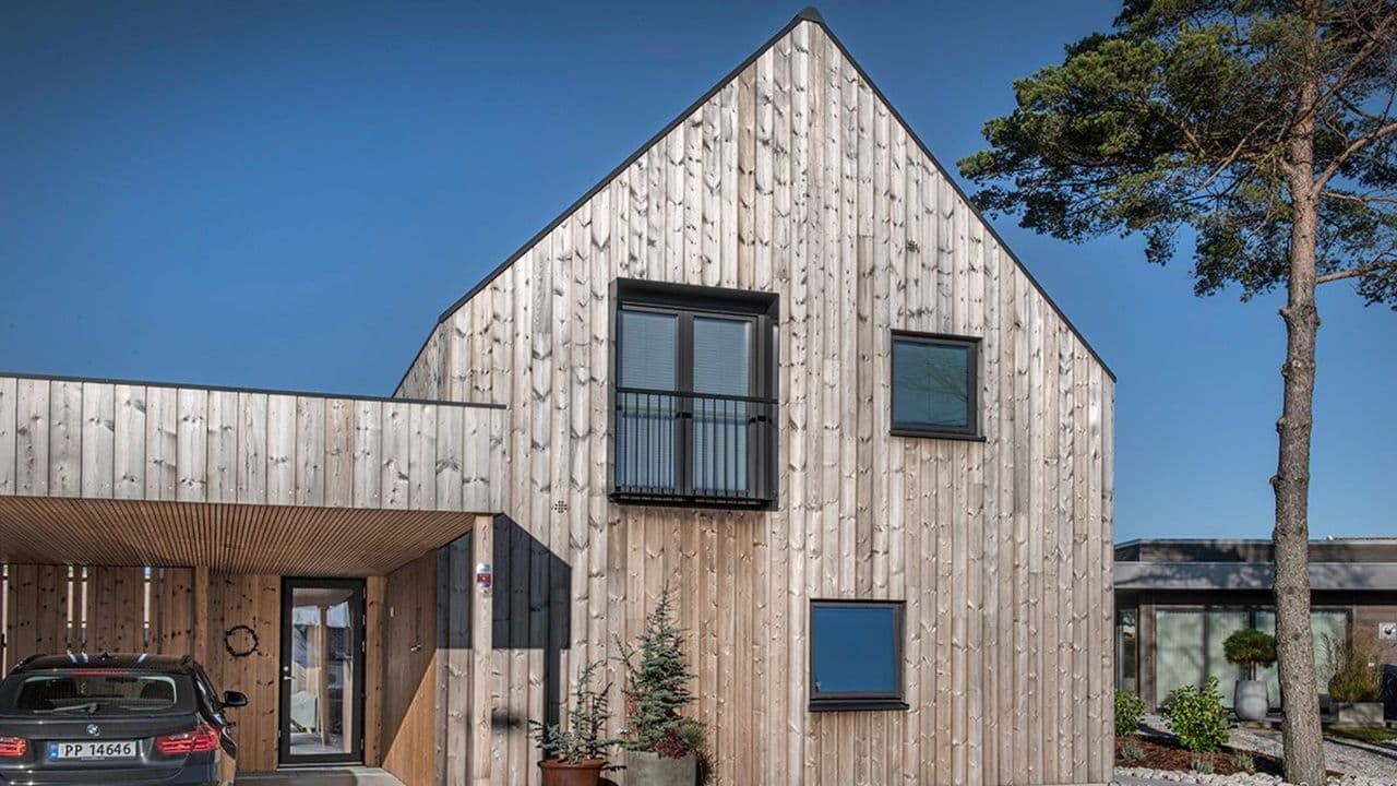 Moderne hus med malmfuru og bil parket utenfor.