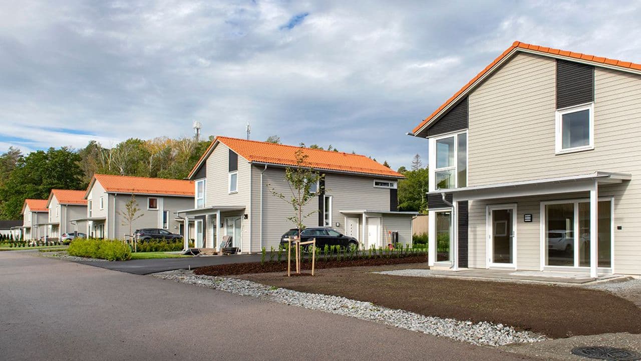 Moderne rekkehus i en idyllisk gate, som alle har ferdigmalt kledning.