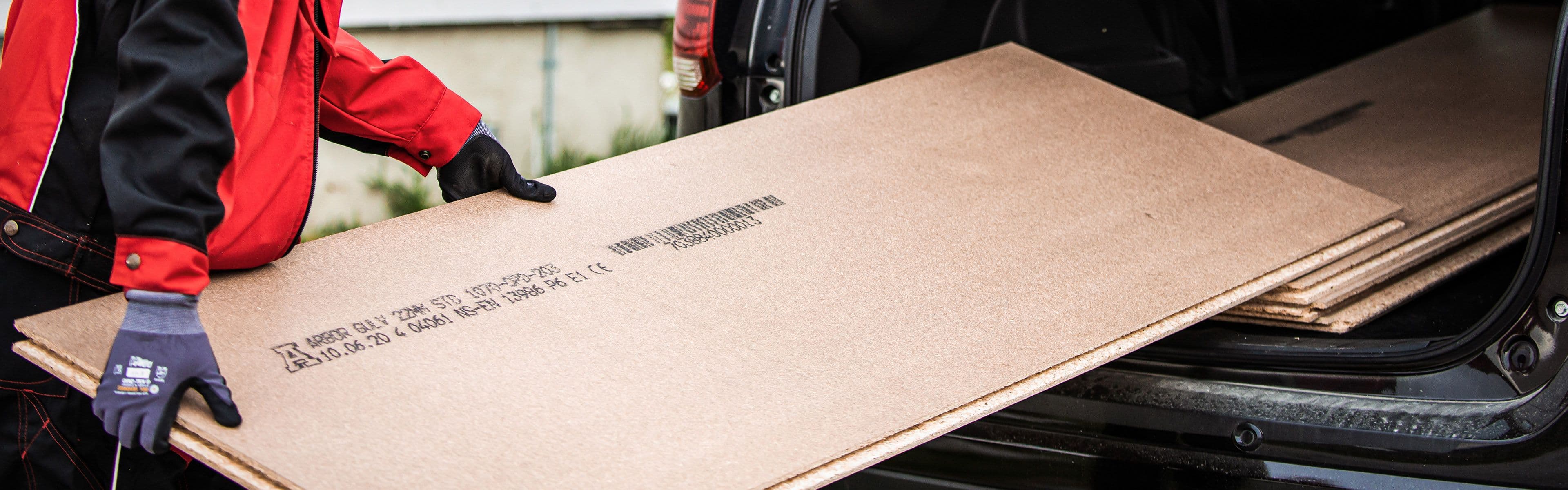 Sponplater som lastes inn i bil av en person.