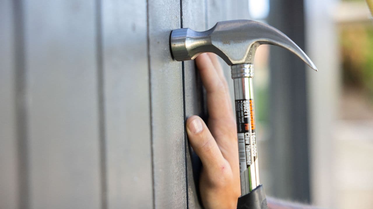 Hånd og hammer på kledning.