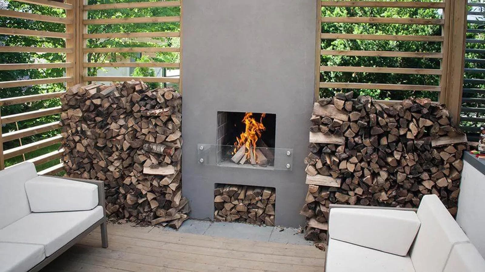 Utepeis i pergola med store stabler ved på sidene og hagemøbler i front.