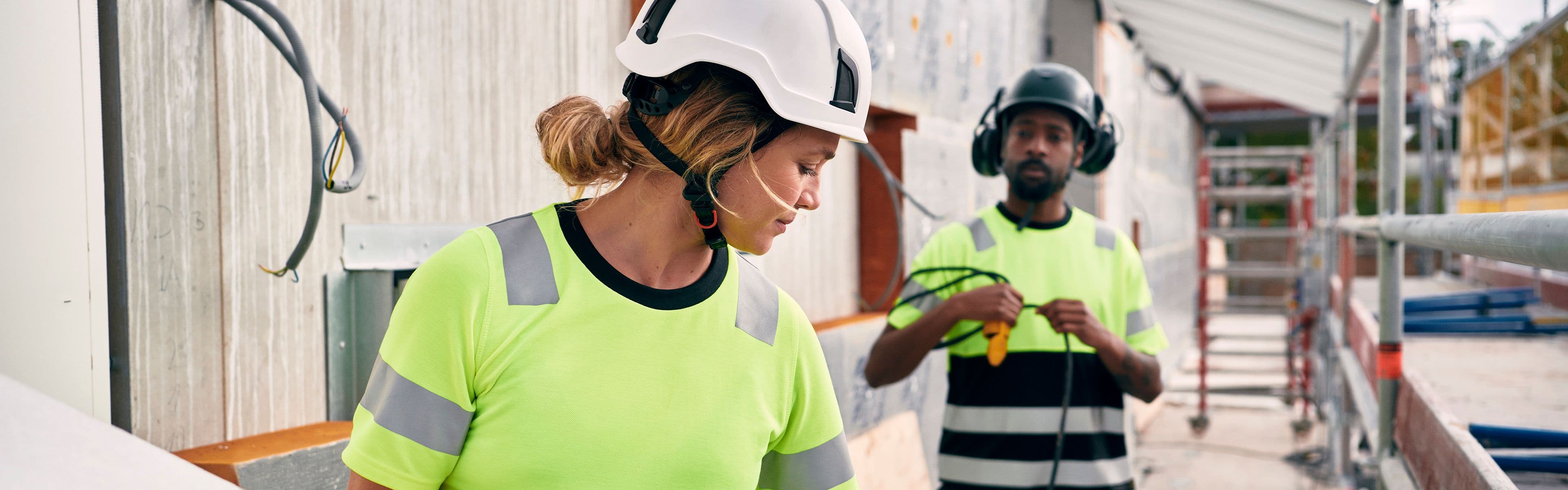 kvinnelig og mannlig håndverker i t-skjorte og shorts på byggeplass
