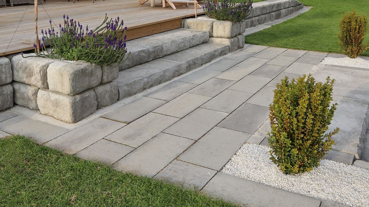 Betongtrapp i hage med belegningsstein og steinheller.