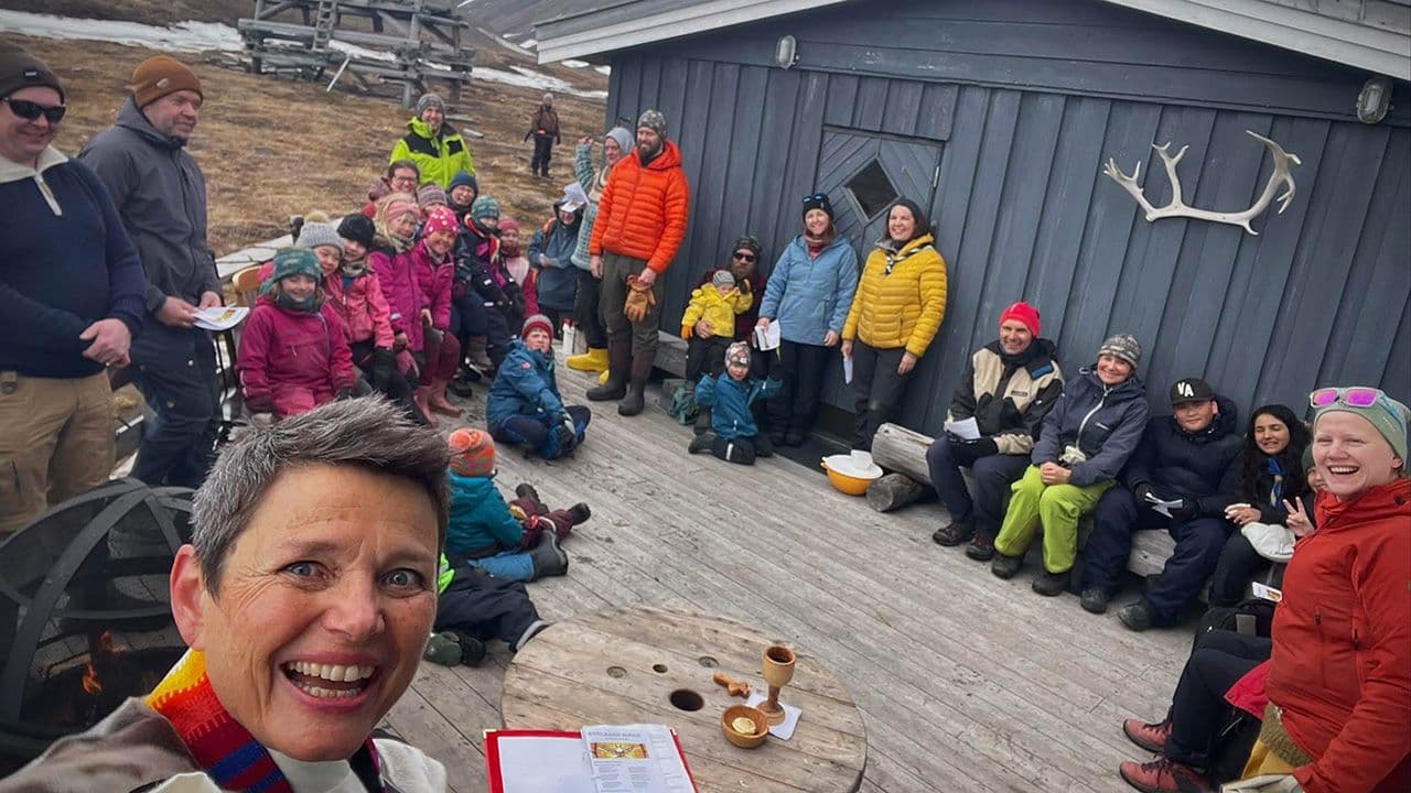 En gjeng med folk som sitter på platting utfor en hytte på Svalbard
