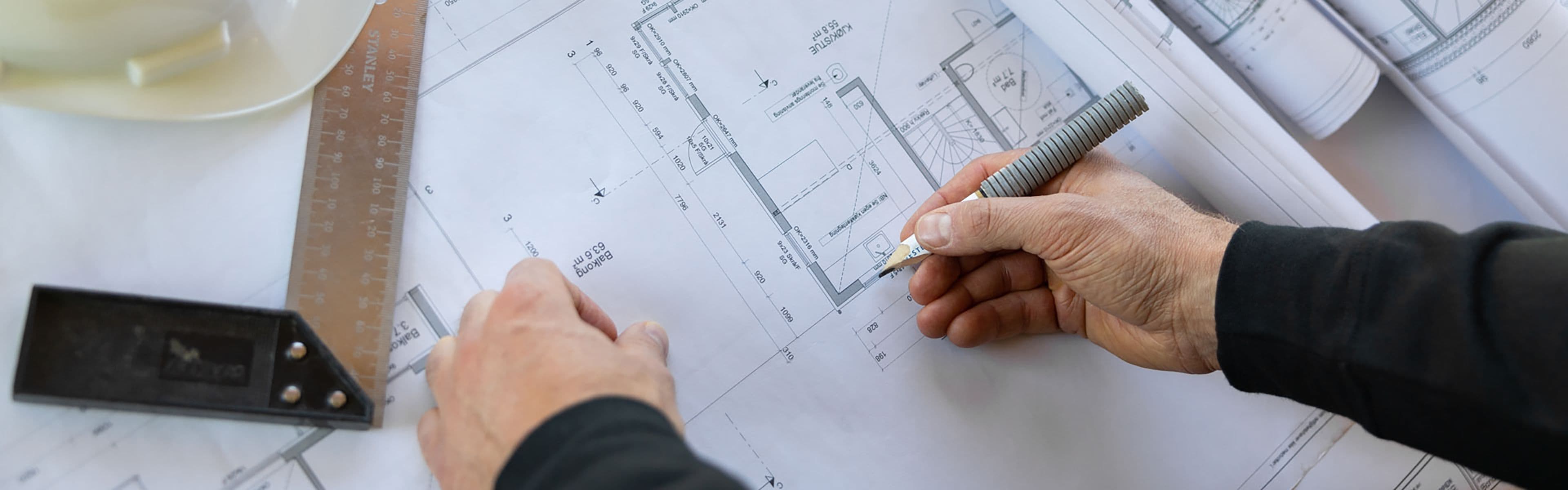 en mann ser på byggetegninger som ligger på et bord