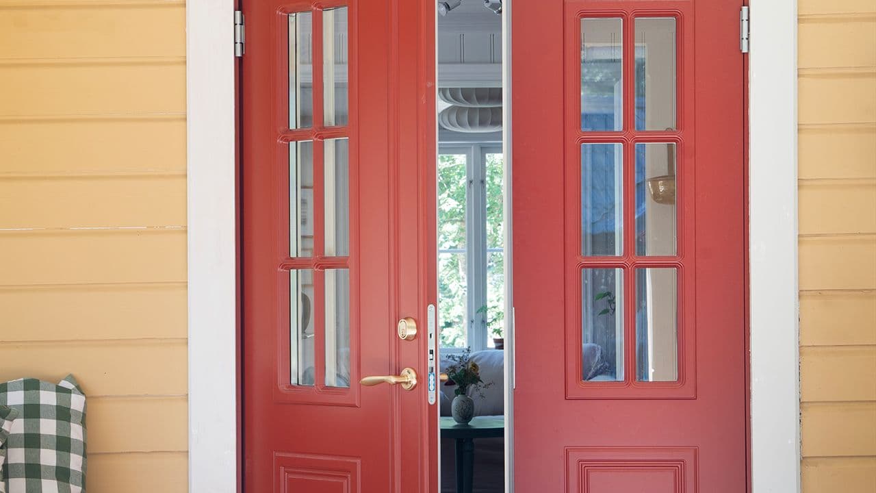Gult hus med klassisk tofløyet ytterdør i rød.
