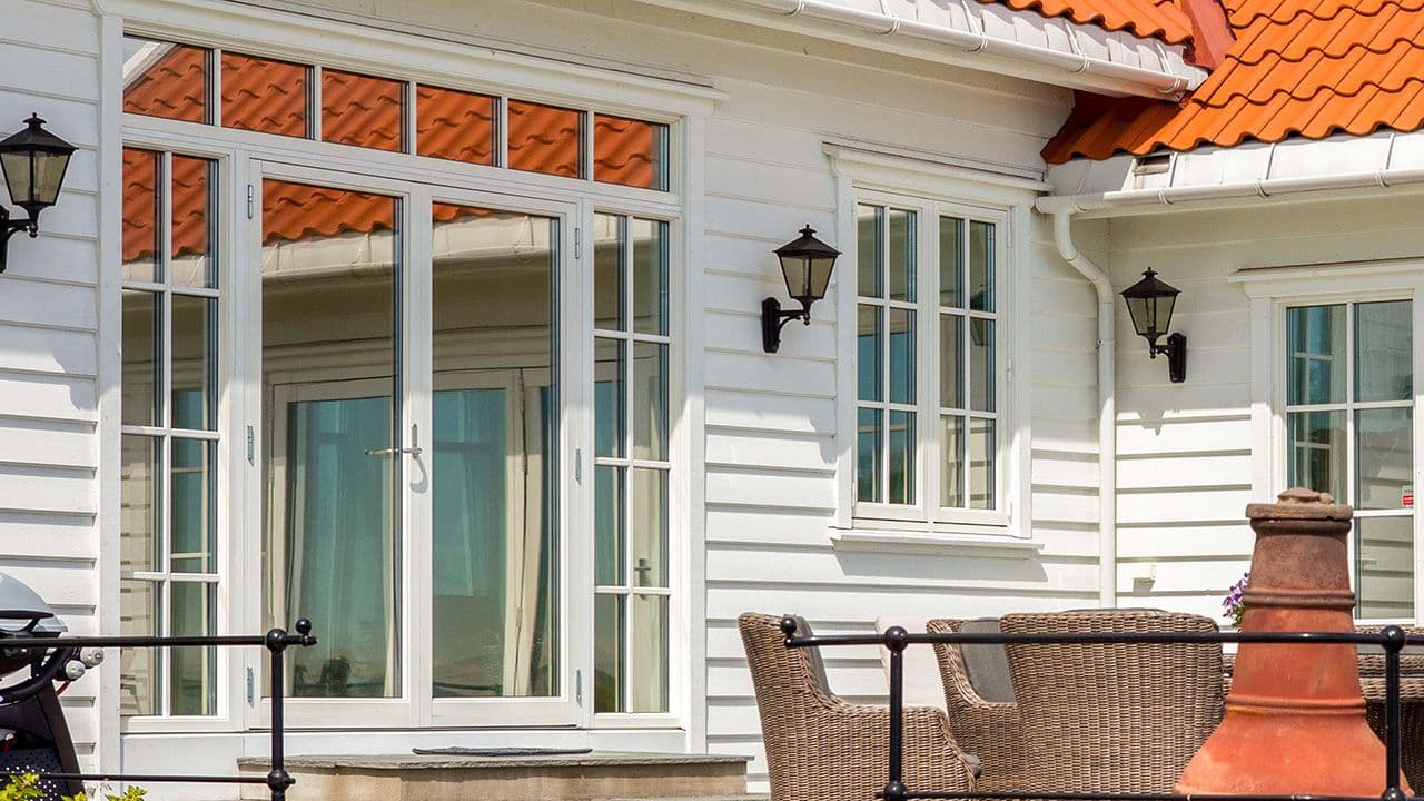 Hvitt hus med dobbel verandadør i helglass og sidefelt med sprosser.