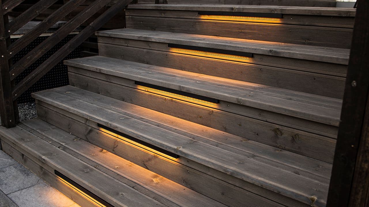 Trapp til terrasse som er lyst opp med utendørsbelysning i trappetrinnene.