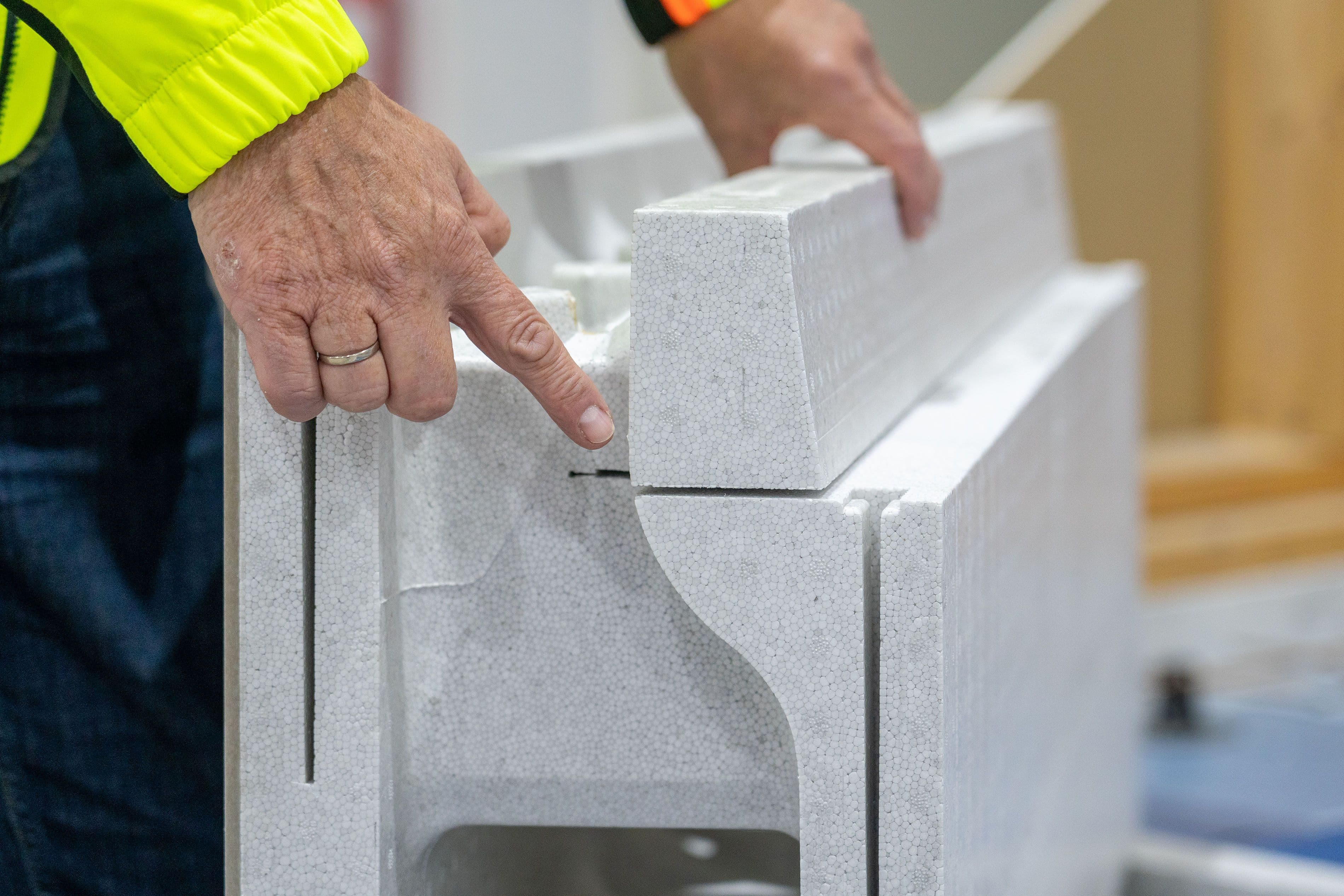 Mann i gul jakke peker på et spor for radonsikring i Jackon Ringmur RA-element