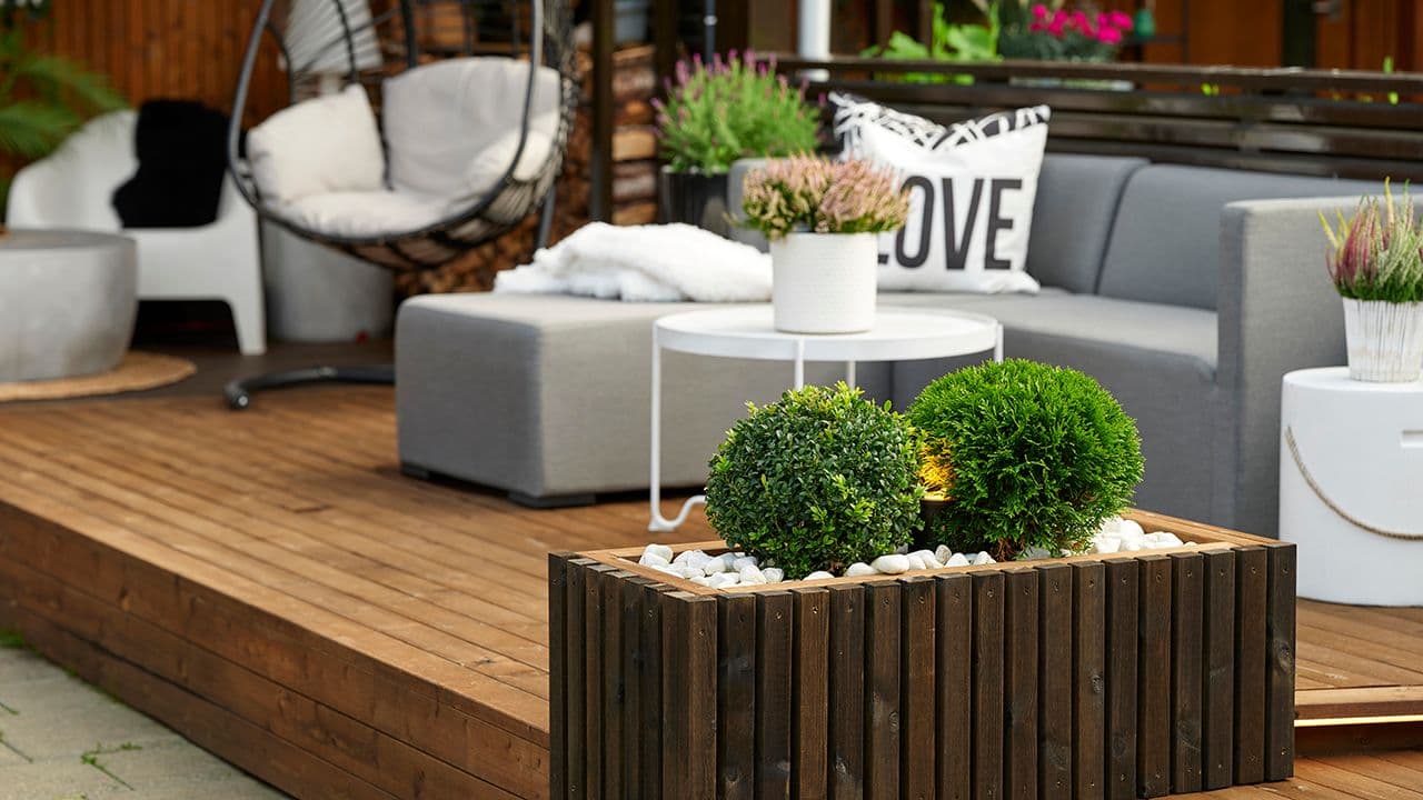 Platting med sittegrupper og hjemmelaget blomsterkasse.