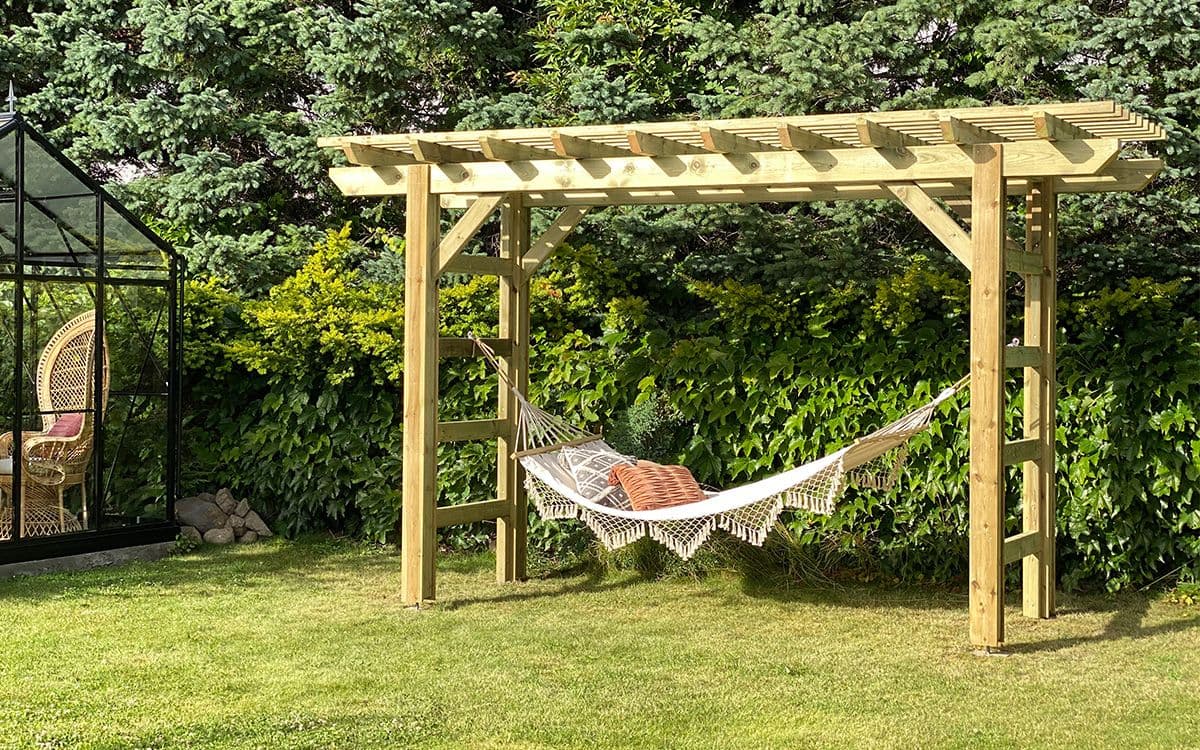 Liten pergola med hengekøye i hage.