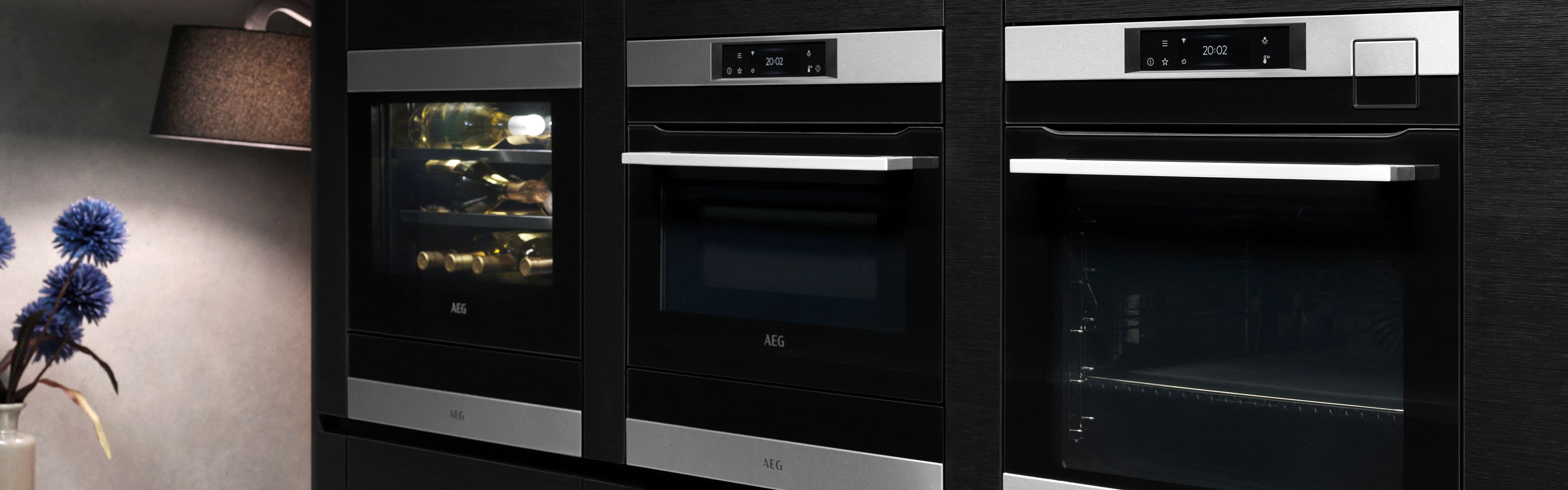 Nærbilde av dampovn og kombiovn i et svart kjøkken.