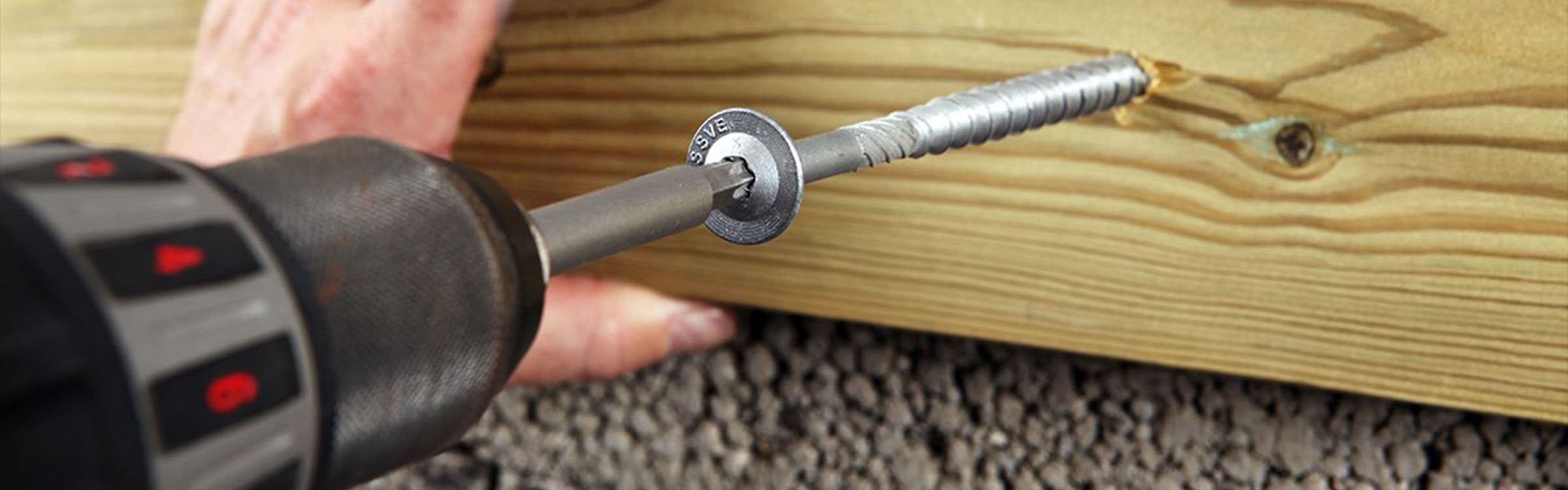 Mann skrur inn en betongskrue fra Essve med drill.