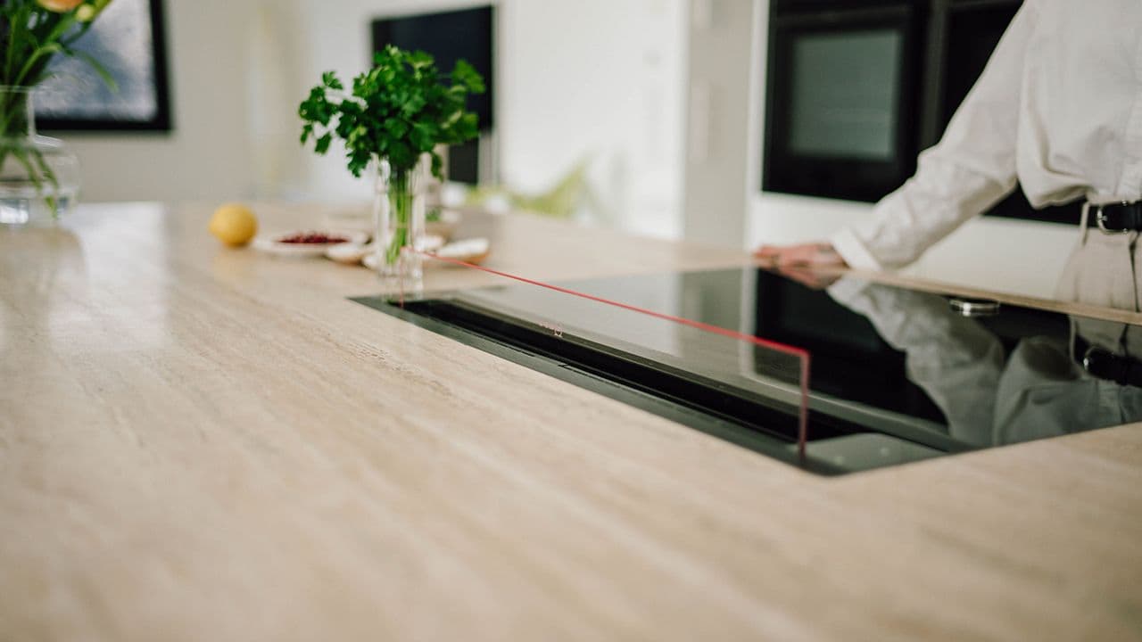 Kjøkkenøy med benkemontert kjøkkenvifte i glass.