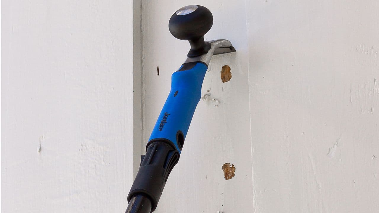 Malingsskrape som skraper maling av husvegg før maling.