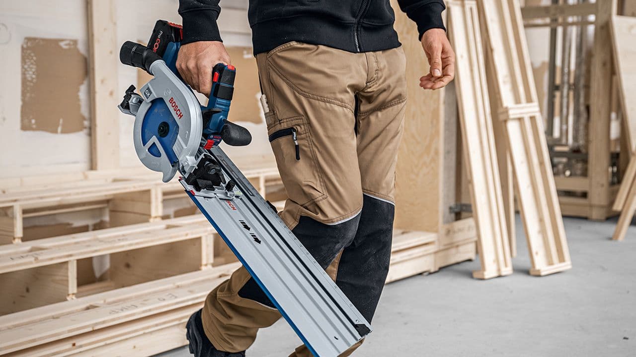 Mann på byggeplass som bærer en blå stikksag.