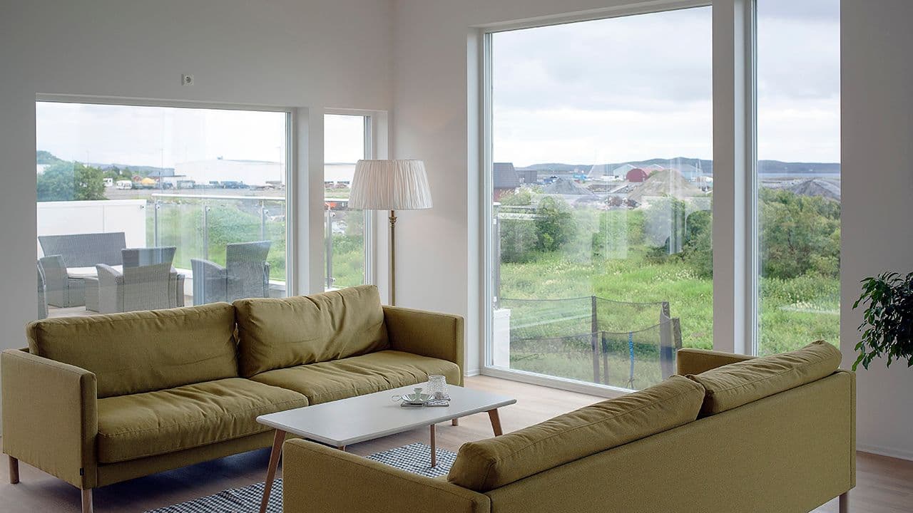 Stue med to sofaer i moderne hus med store vindusflater.