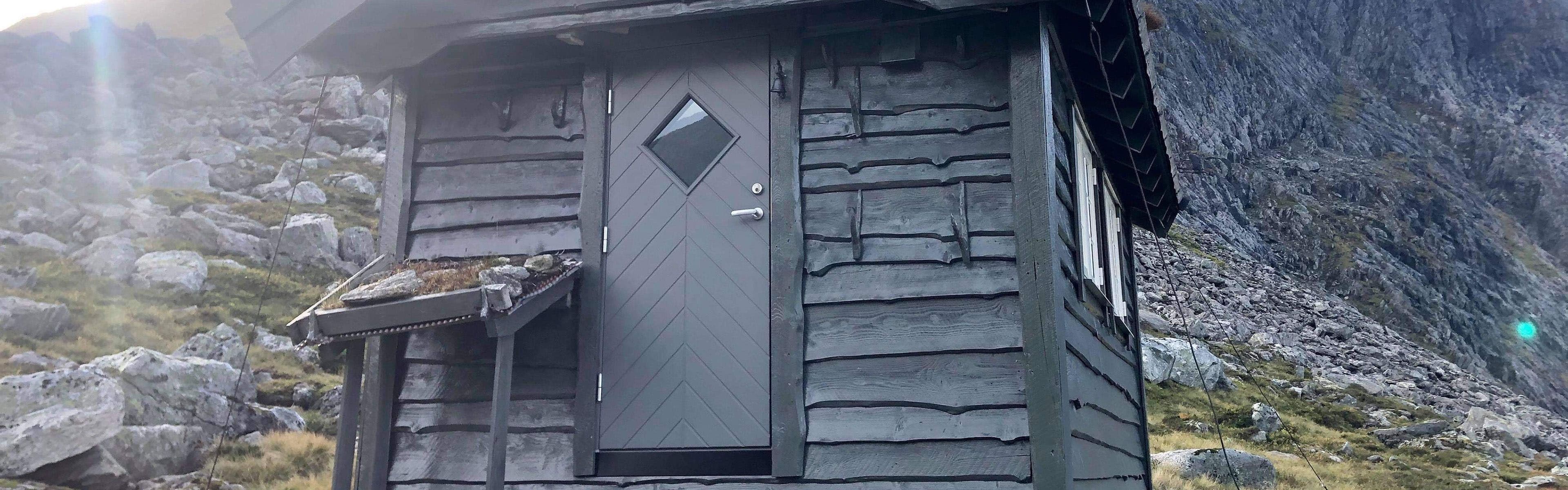 Grå ytterdør på en liten hytte i fjellheimen.