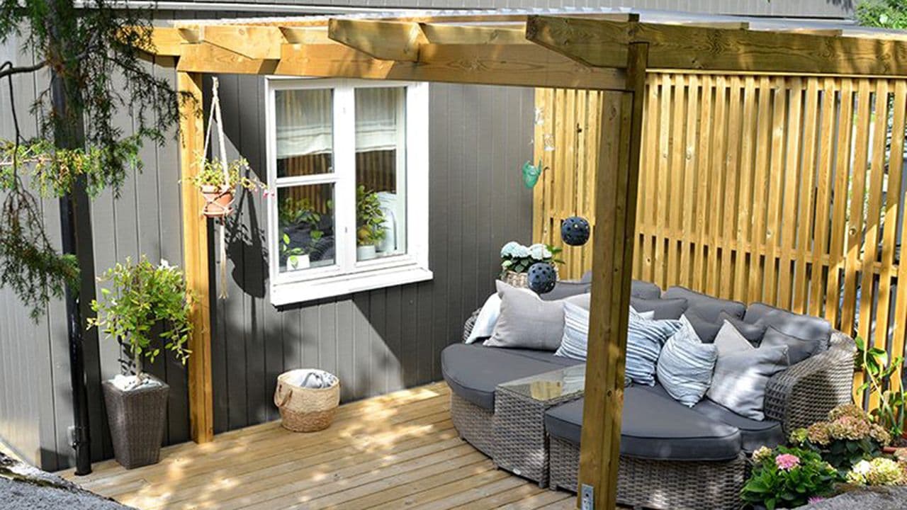 Platting med pergola ved siden av husveggen.