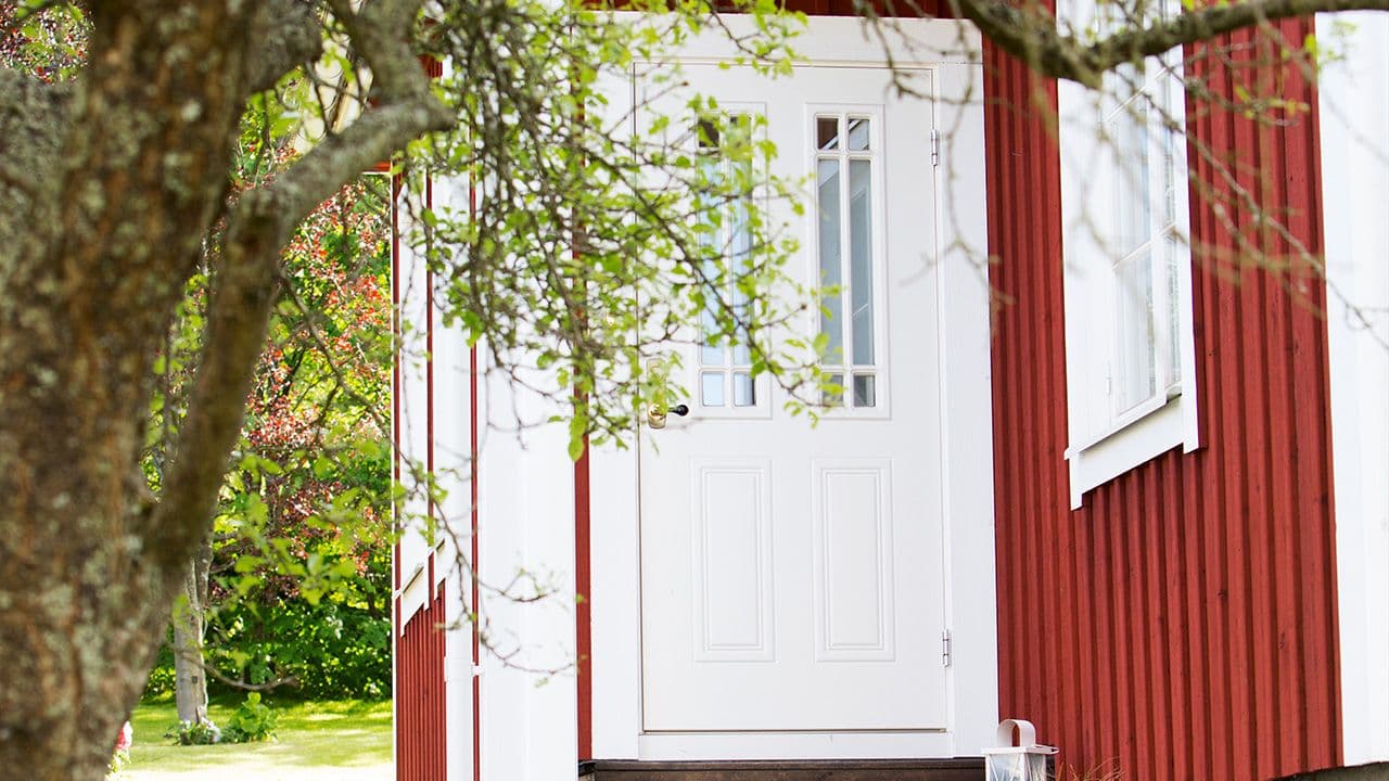 Rødt hus med klassisk hvit ytterdør med glassfelt og sprosser.