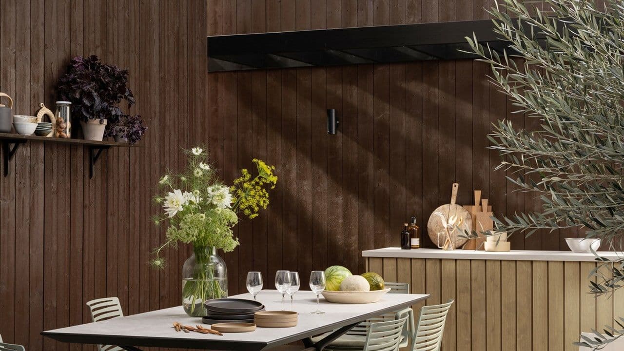 Husvegg malt med TREBITT beis utendørs i fargen 0676 Tjærebrun og utekjøkken i TREBITT beis 9074 Nordisk Tre.