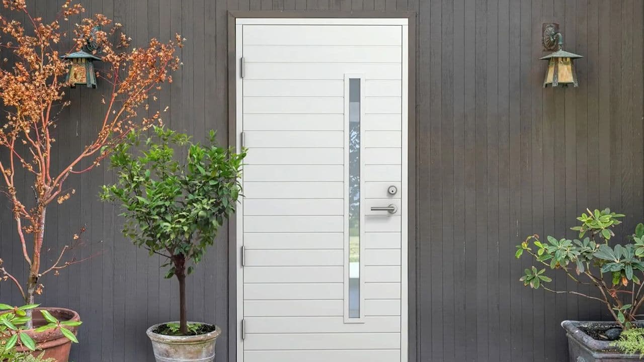 Hvit ytterdør med glassfelt på trehus med stående kledning.