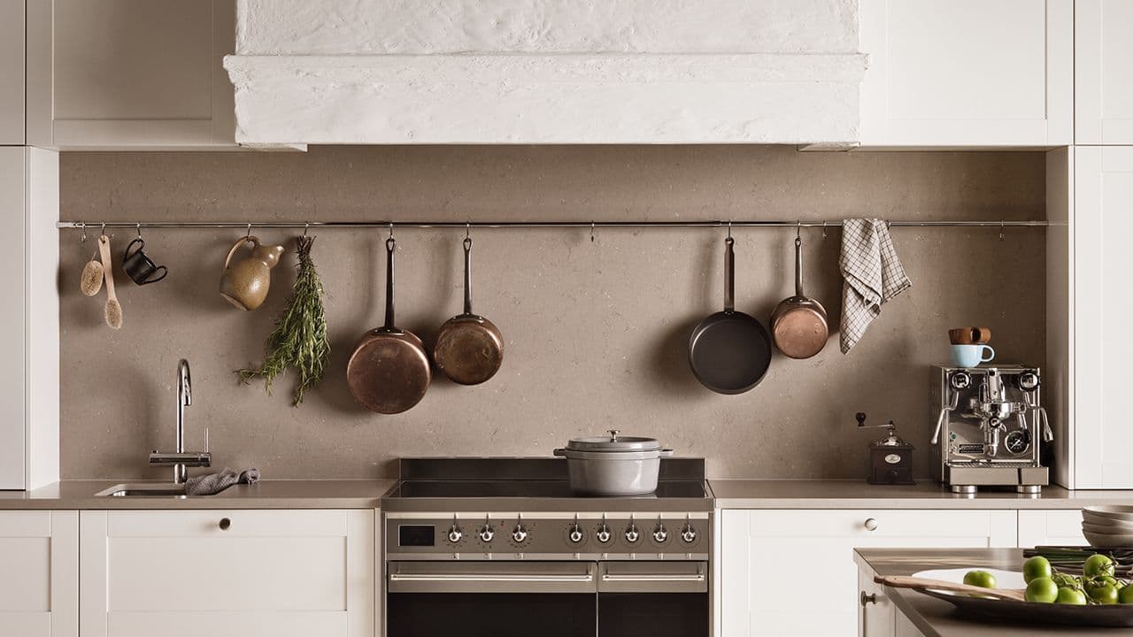 Lyst landlig hyttekjøkken med stekeovn, kaffemaskin, servant og blandebatteri i krom.