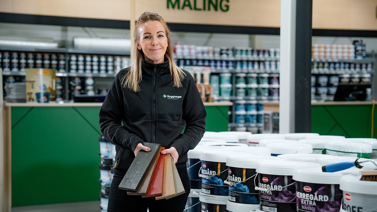 Byggtorget ansatt viser frem prøver på beis til uterom.