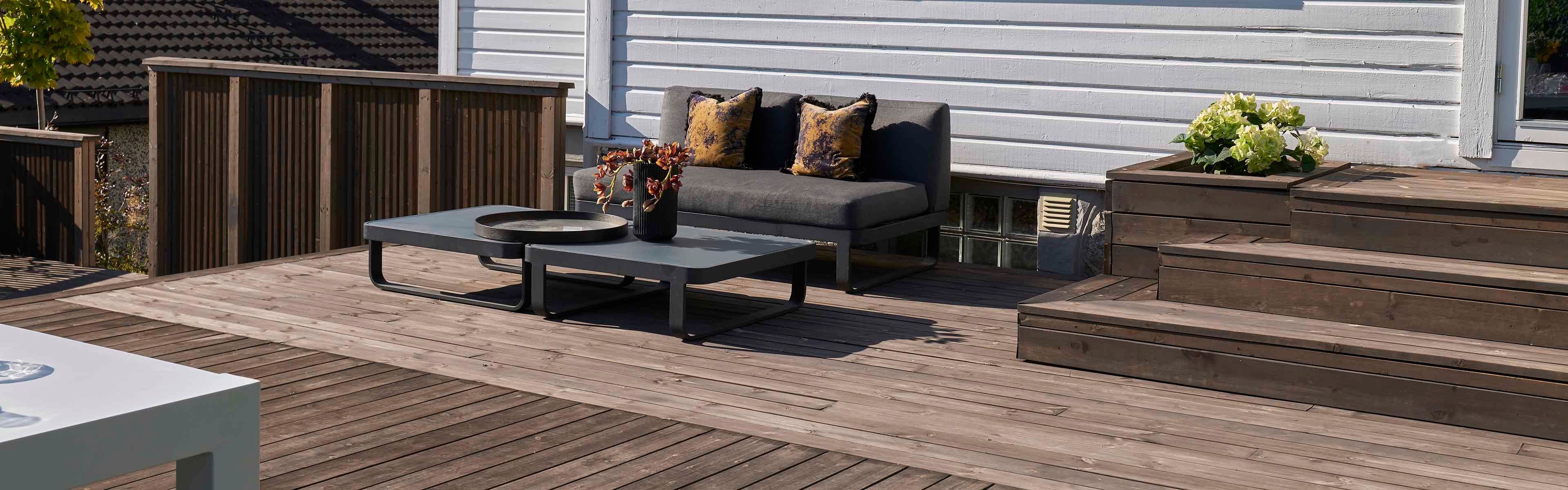 Terrasse med trapp, rekkverk og sittegruppe.