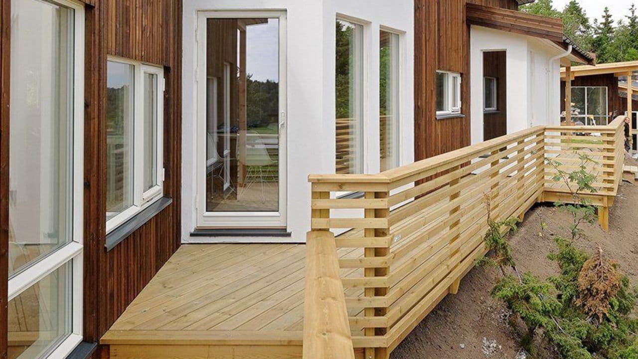 Rekkverk i tre langs terrasse til husvegg.