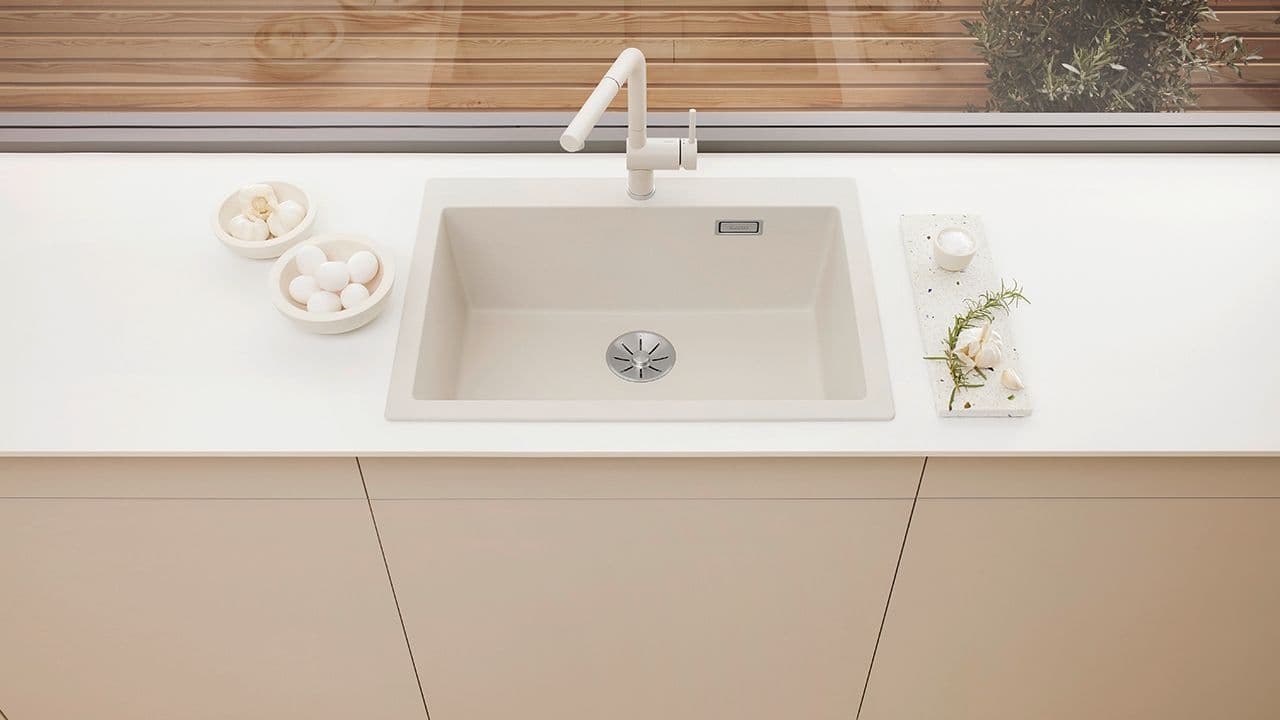 Hvit kjøkkenvask i samme farge som benkeplaten i lyst kjøkken.